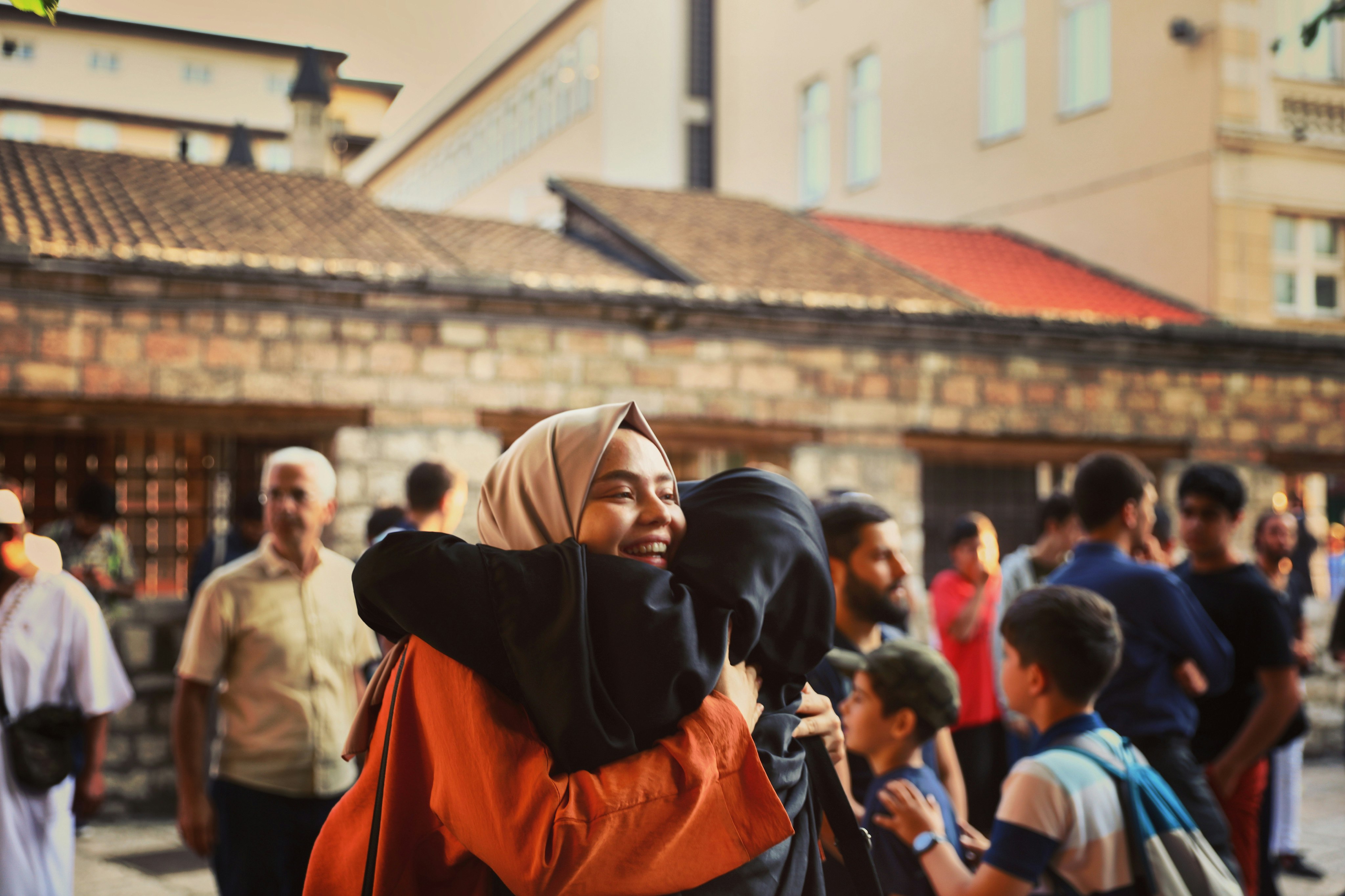 man in orange and black hoodie covering his face with his hand